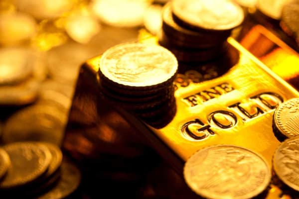A gold bar sitting on a stack of gold coins