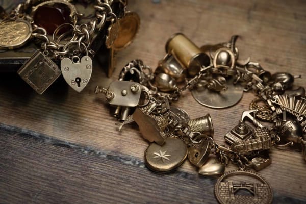 Gold charm bracelets, on a wooden desk