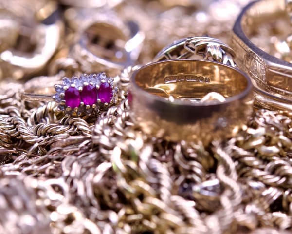 A pile of scrap 9ct gold with focus on a hallmark