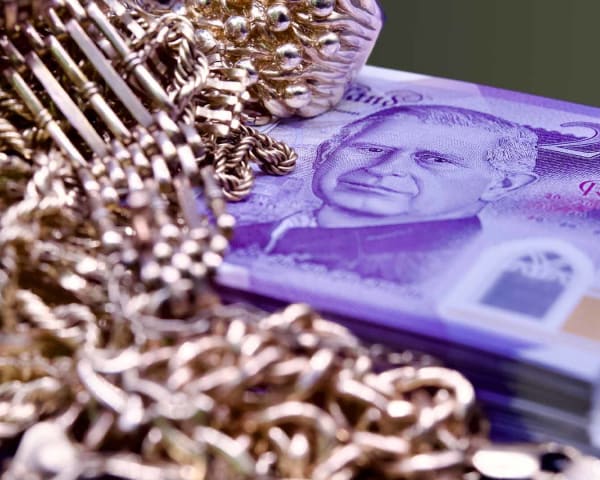 A pile of scrap gold, sitting on top of a bundle of £20 notes