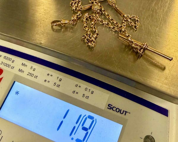 A vintage gold 'Albert' chain being weighed on precision scales