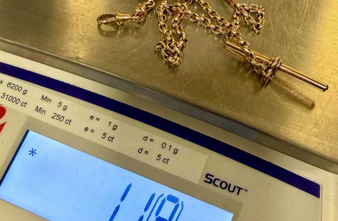 A vintage gold 'Albert' chain being weighed on precision scales