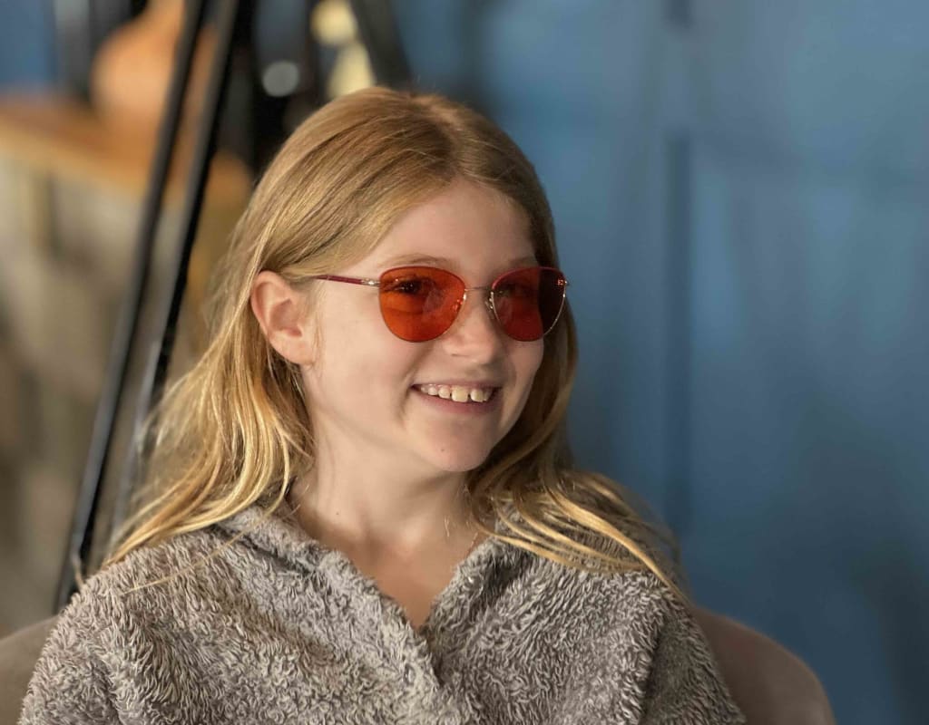 Young girl looking happy and relaxed in coloured lenses for her visual stress