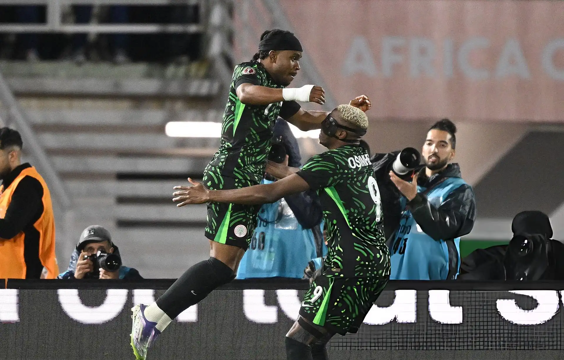 Disappointed Nigerian football player sitting on pitch in empty stadium