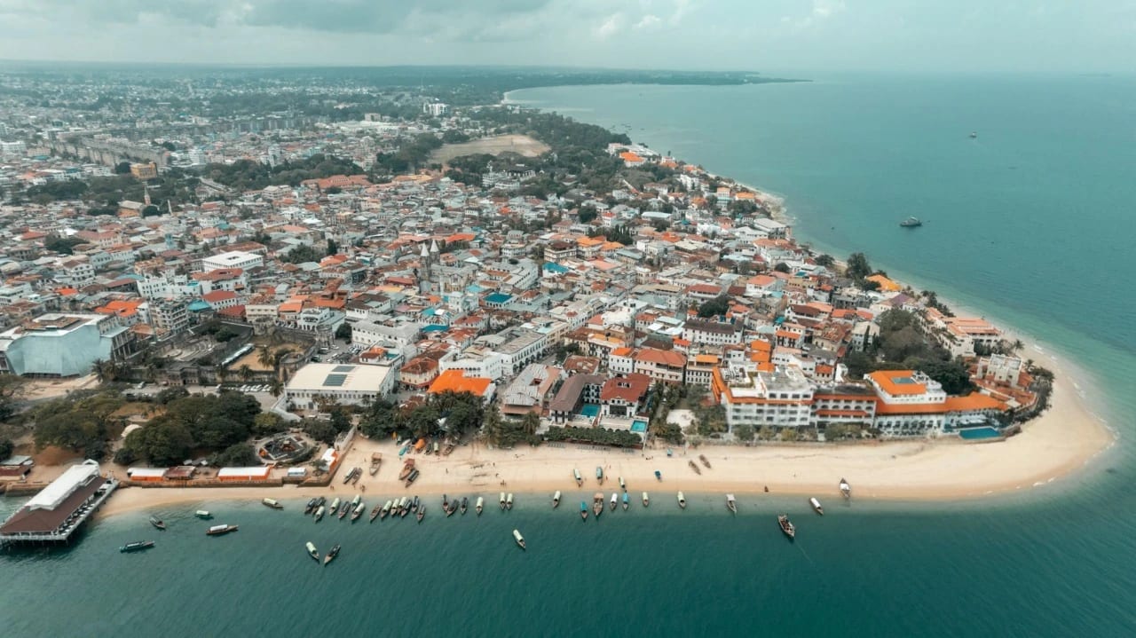 Luftaufnahme des Zanzibars-Paradieses mit Dächern der Stone Town, türkisfarbener Küstenlinie, Booten und lebendigem Grün.”