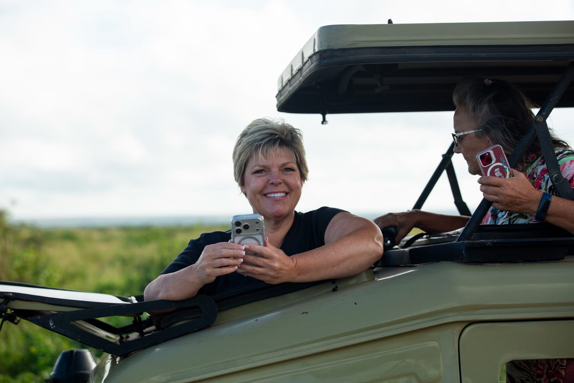 A woman smiling from the window of a safari vehicle with the roof open
