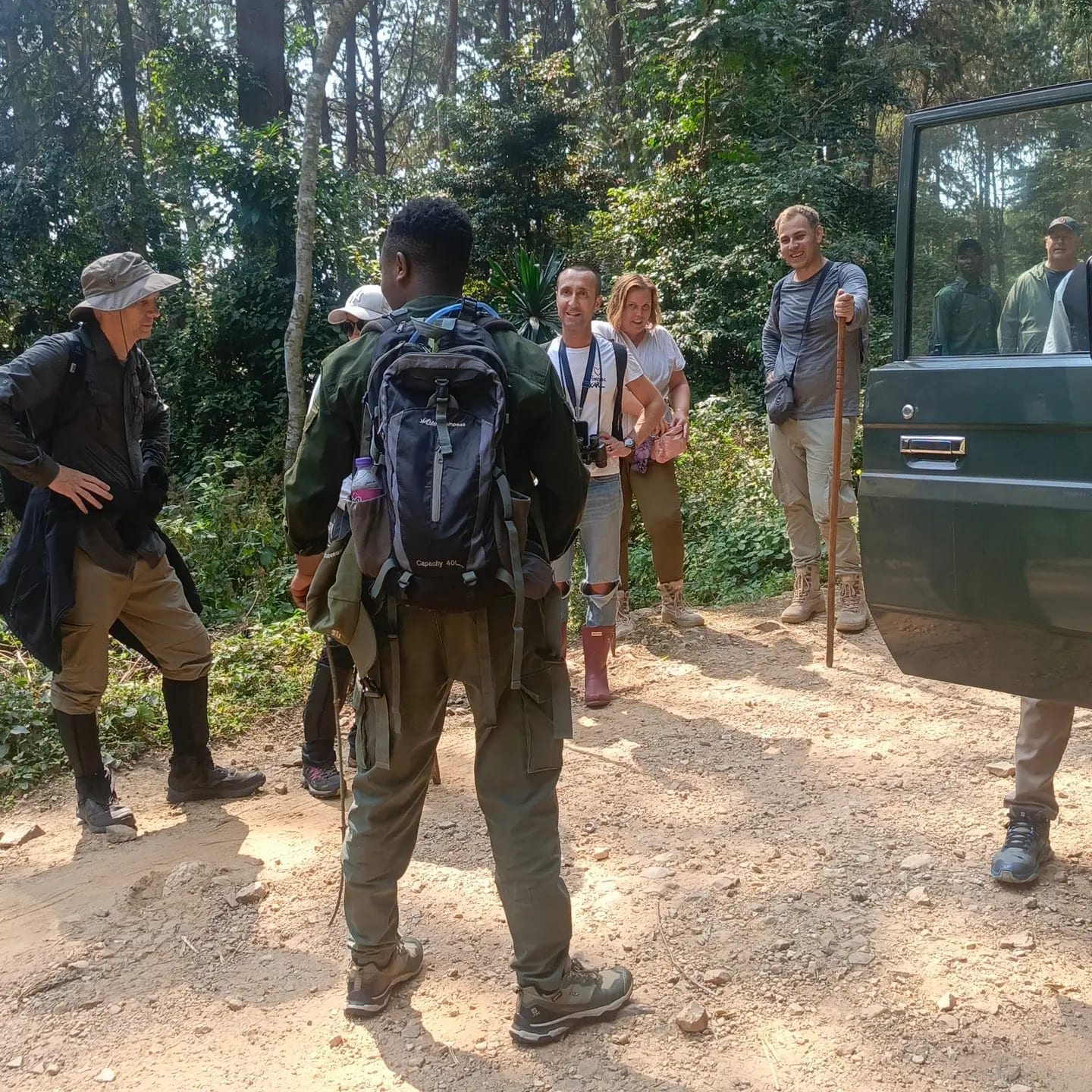 A guide and guests beside a safari vehicle at the start of a forest walk