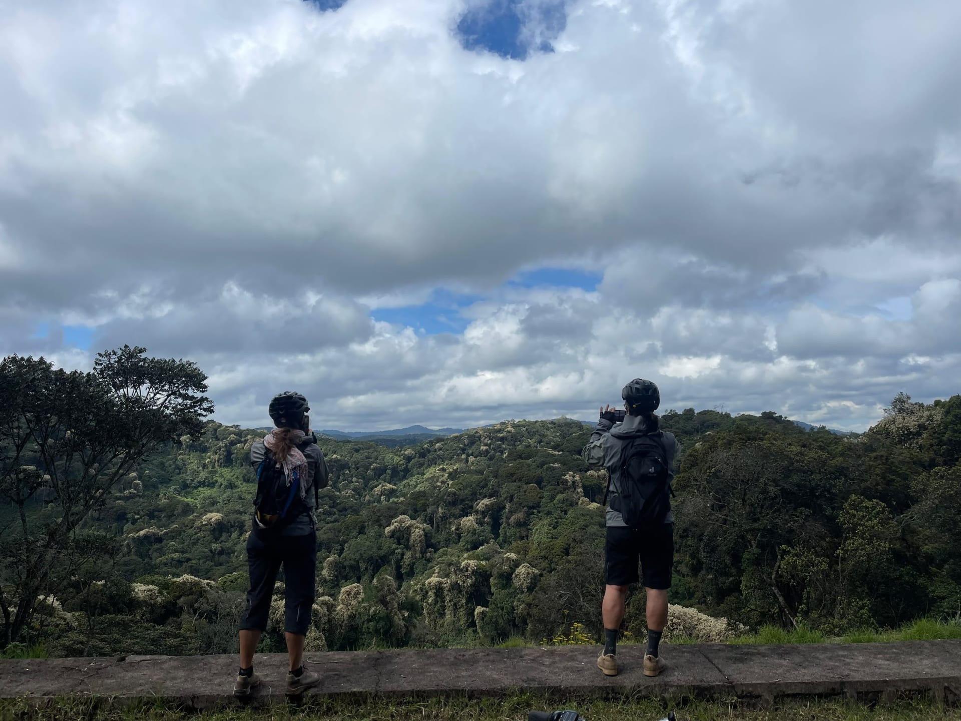 Two hikers looking out over green hills on the Congo Nile Trail in Rwanda