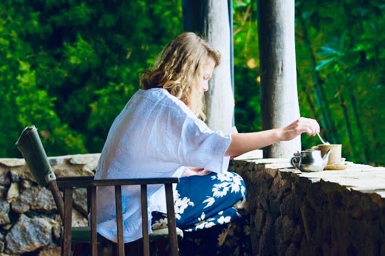 Reisende Frau genießt ein luxuriöses Eco-Lodge-Frühstück mit knusprigem Speck in Ruanda, umgeben von Natur und morgendlicher Ruhe.