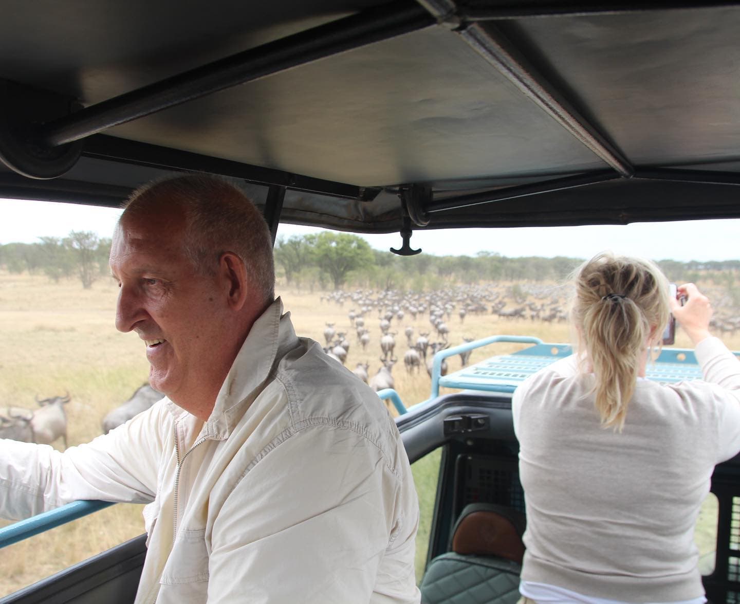 Guests in a safari vehicle watching a large herd on the plains in Tanzania