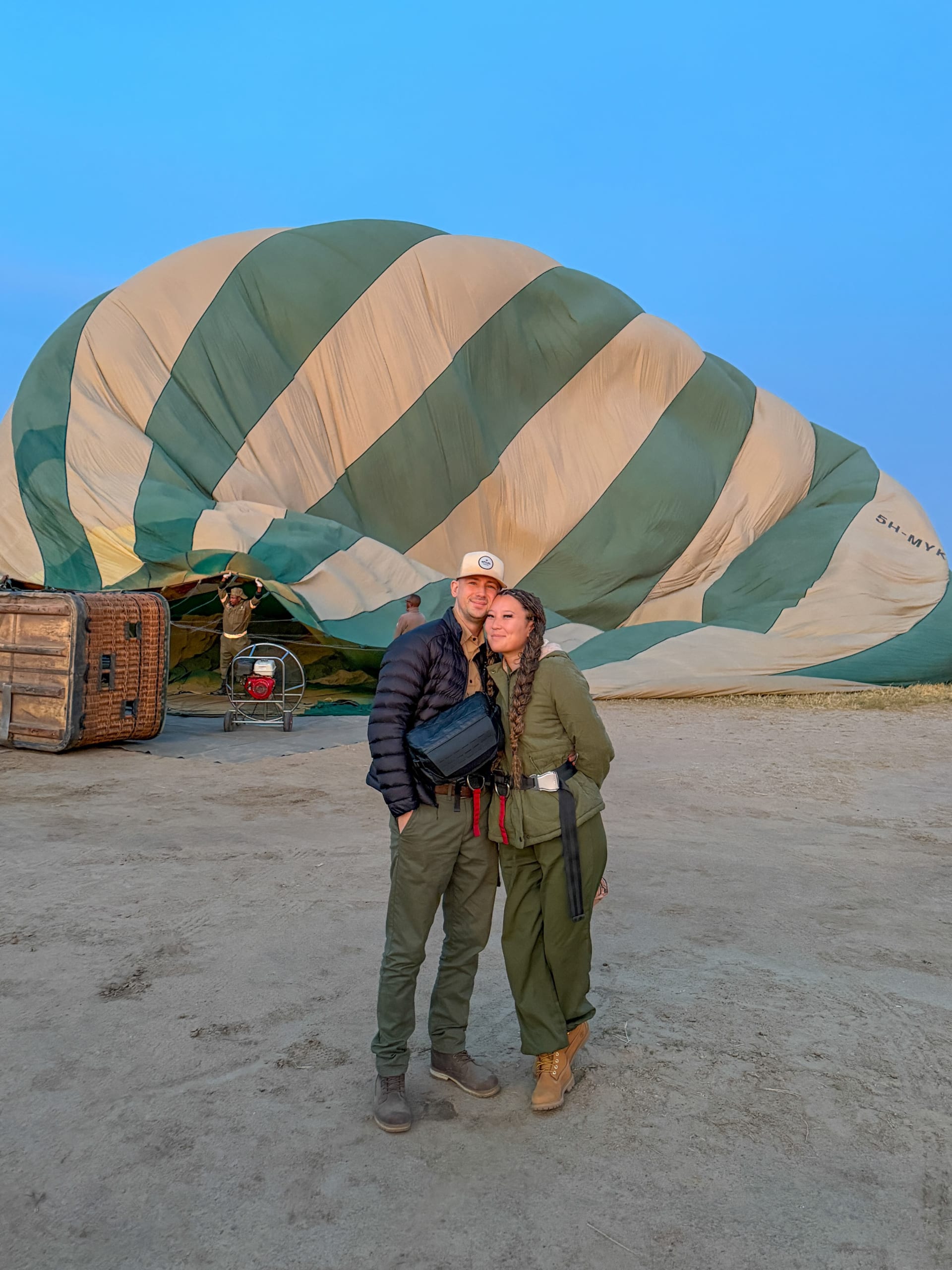 A couple standing beside a hot-air balloon being inflated before a flight