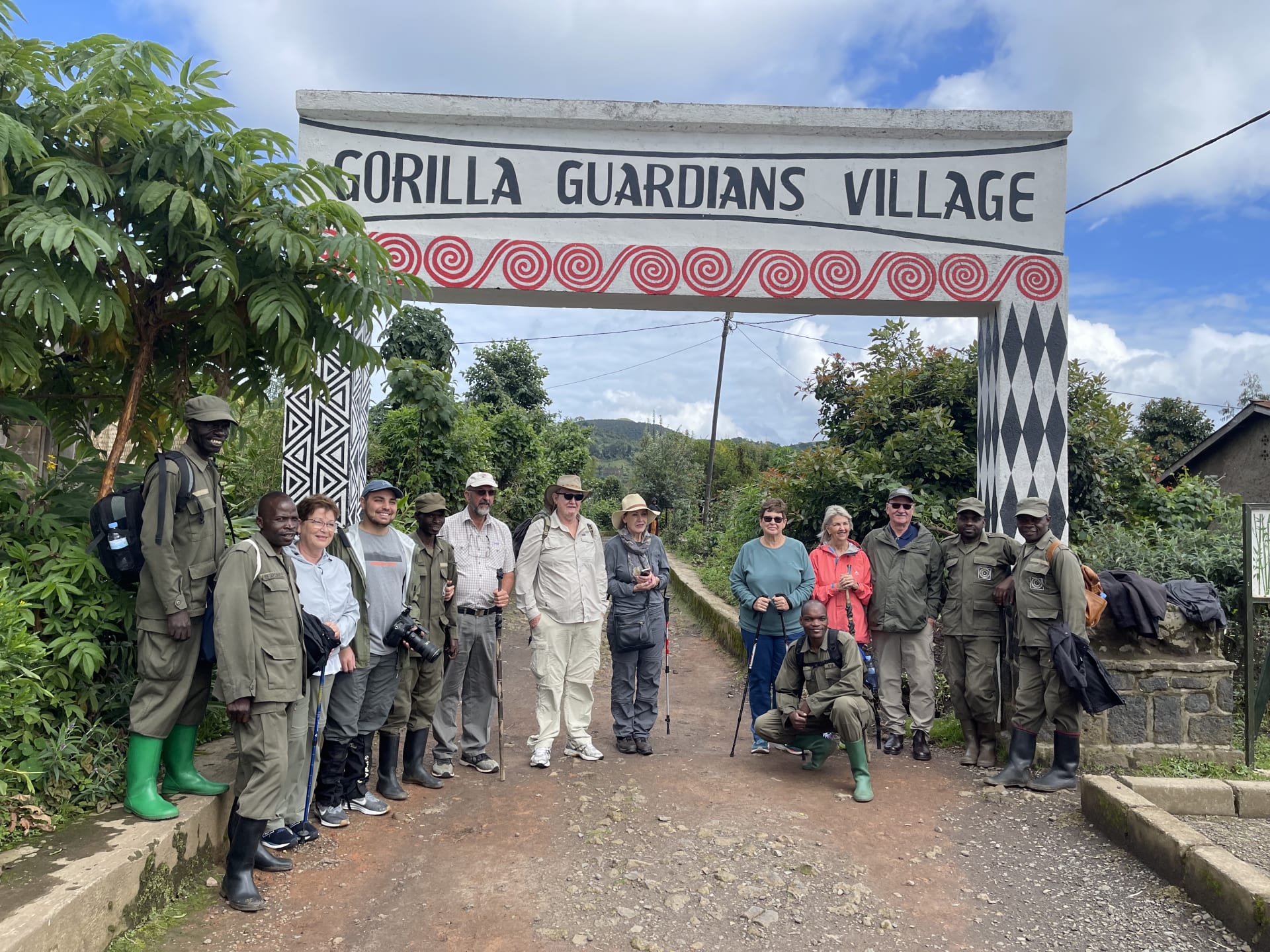 Visitors and rangers standing under the Gorilla Guardians Village sign near Musanze, Rwanda