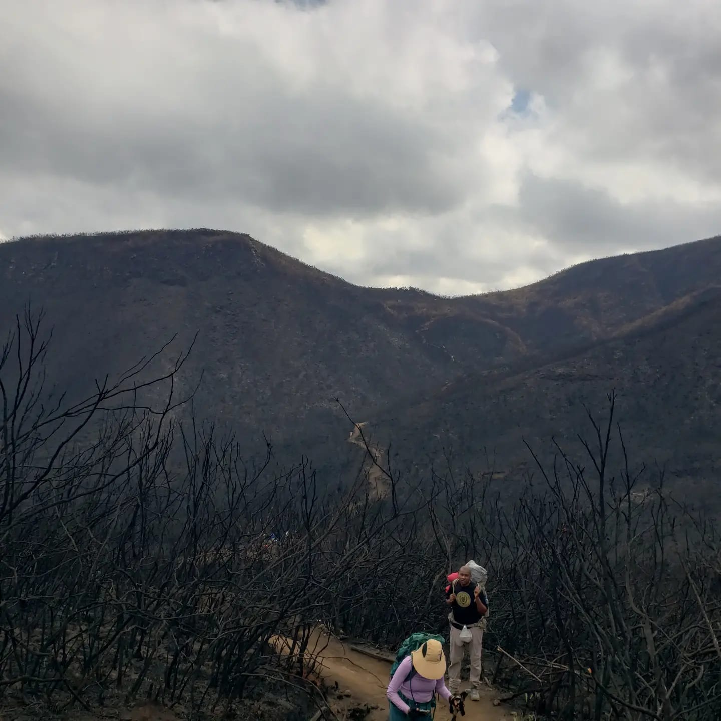 A hiker on a dark slope on Mount Kilimanjaro under cloud