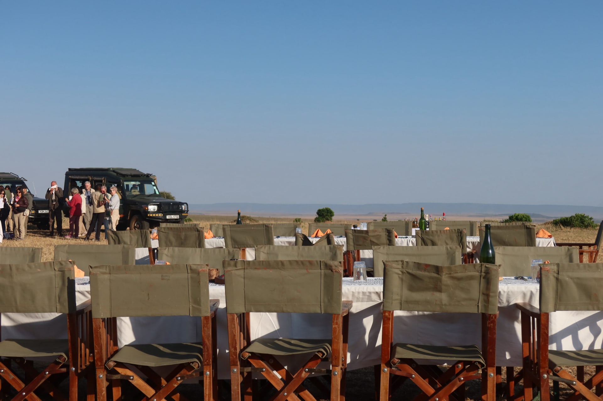 Une longue table à manger dressée avec des chaises safari sur les plaines ouvertes