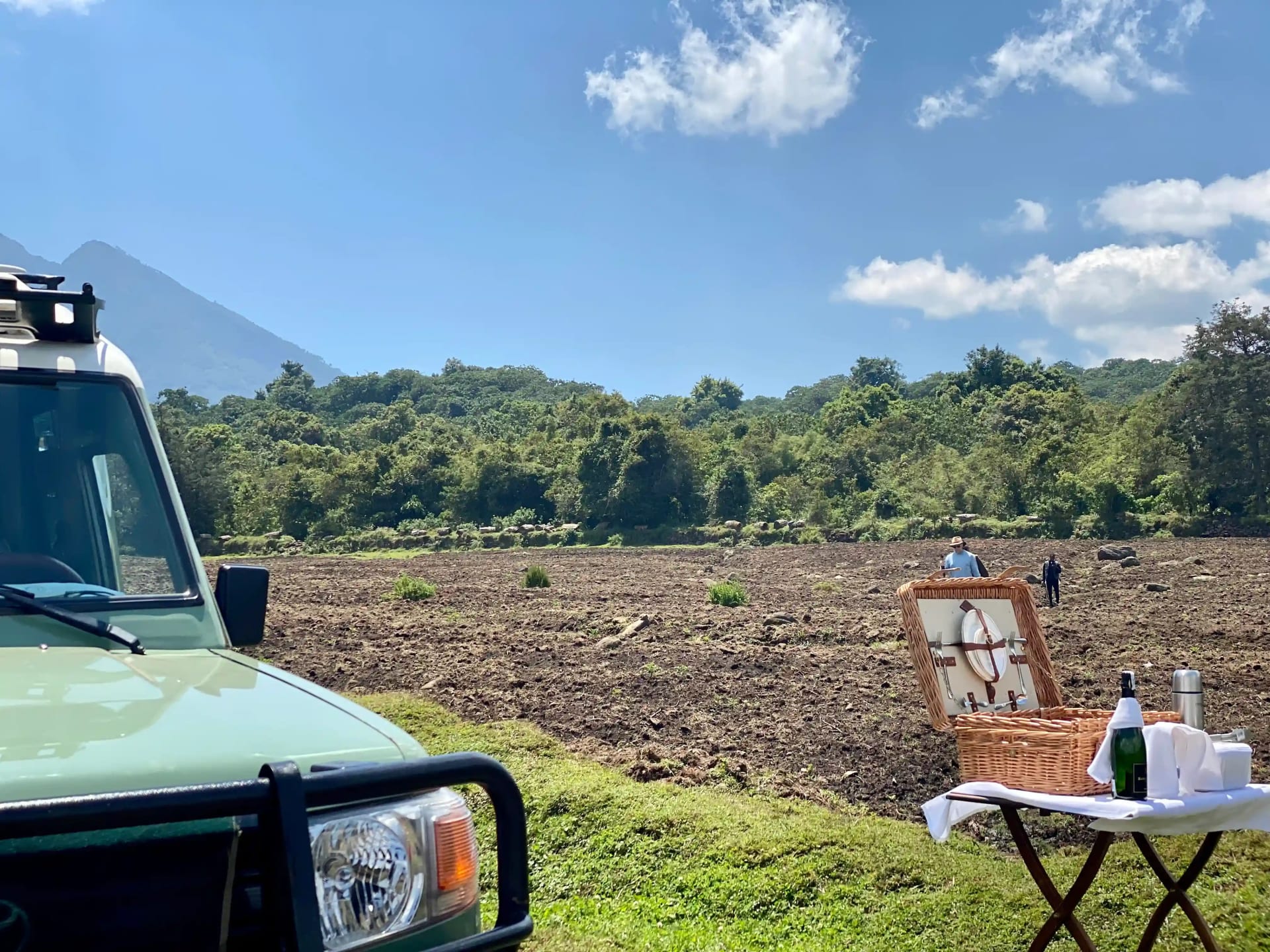 Luxus-Safari-Fahrzeug mit Weinaufbau auf dem Tisch, das auf Gäste wartet, die von der Berggorilla-Trekking-Tour in Ruandas Volcanoes National Park zurückkehren.