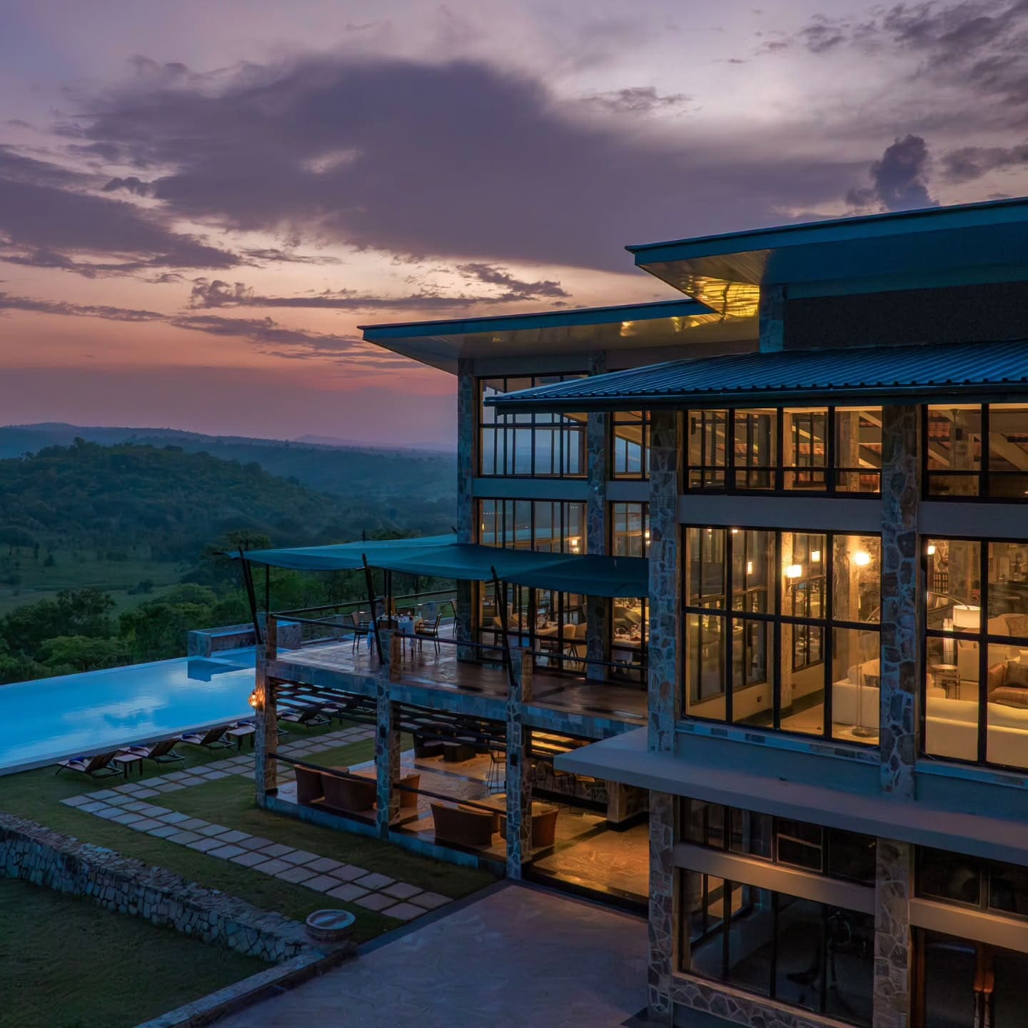 A modern lodge building and infinity pool at dusk in Tanzania