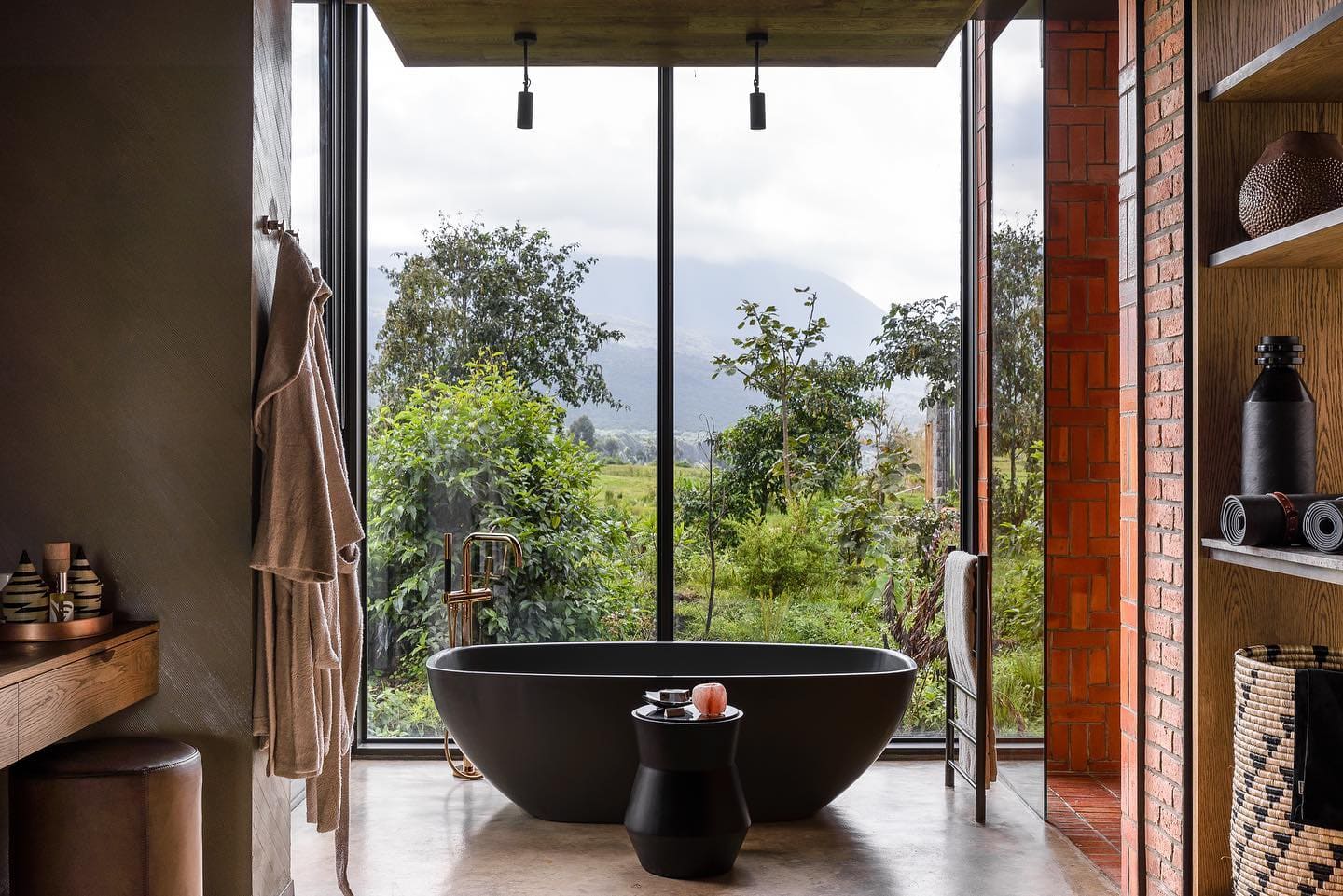 A suite bathroom with a bath and a forest view at a luxury lodge near Volcanoes National Park