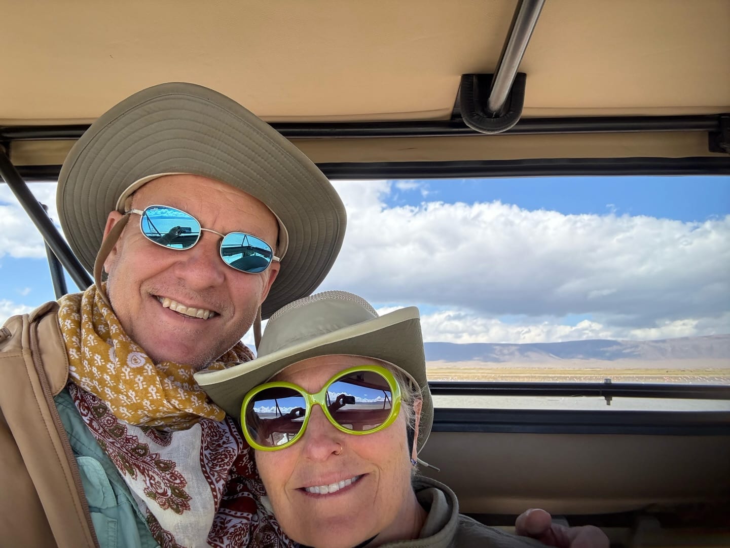 A couple in hats taking a selfie in a safari vehicle in Tanzania