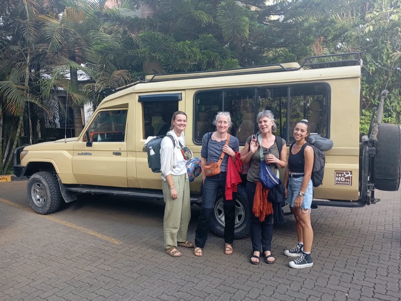 Five guests standing in front of a safari van at a lodge car park