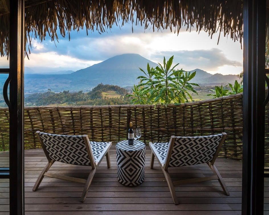 A lodge balcony with two chairs facing a Virunga volcano in Rwanda
