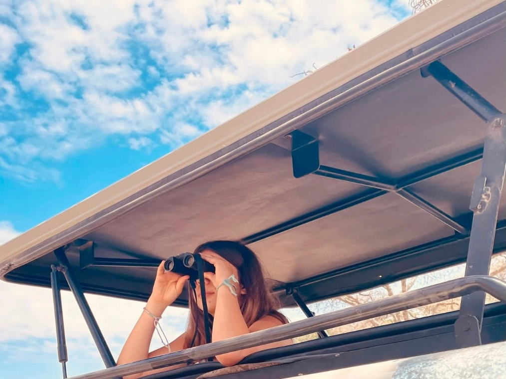 Una joven hija observando la gran migración a lo lejos con binoculares