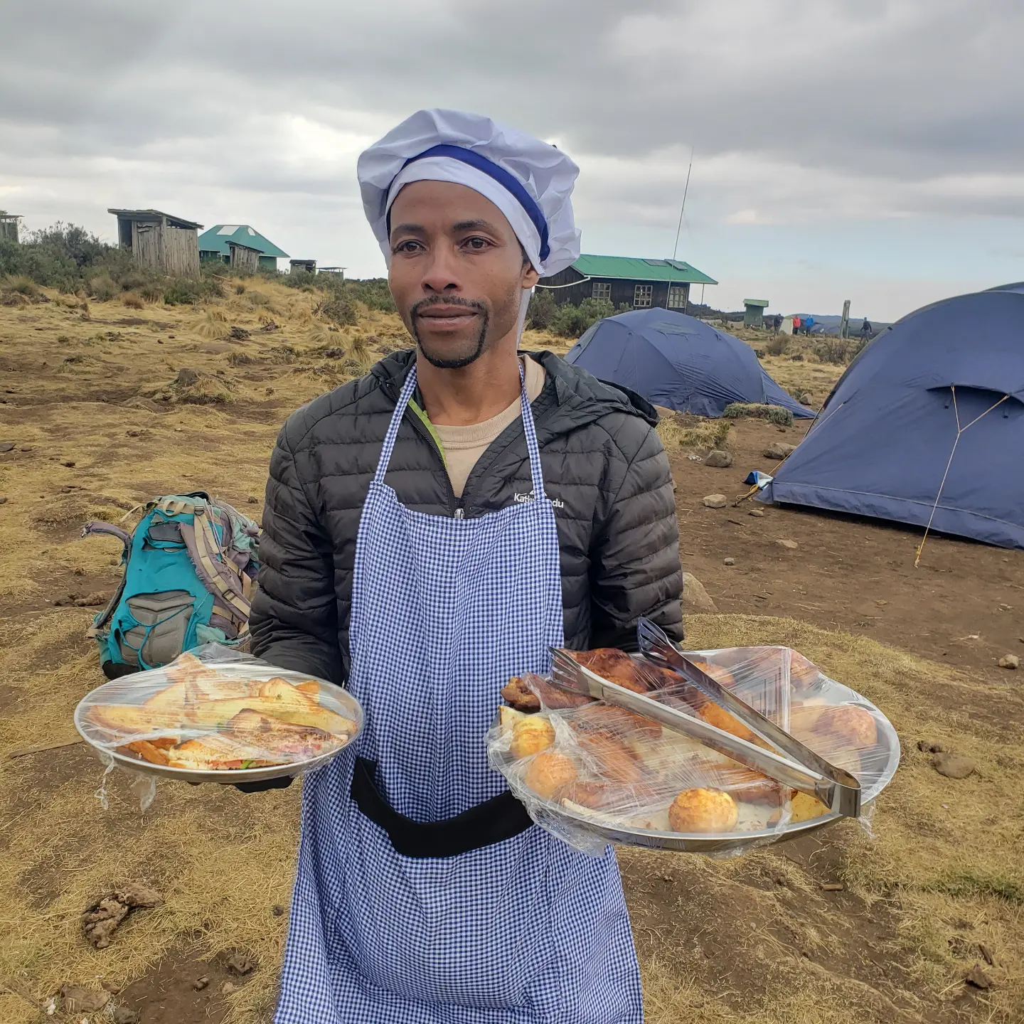 A mountain cook carrying breakfast trays at a camp on Kilimanjaro