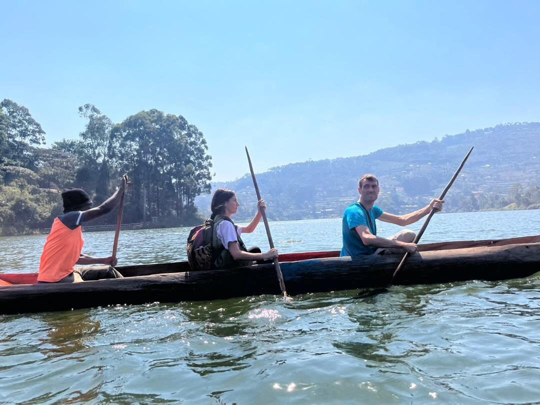 Guests and paddlers in a dugout canoe on a lake in Rwanda