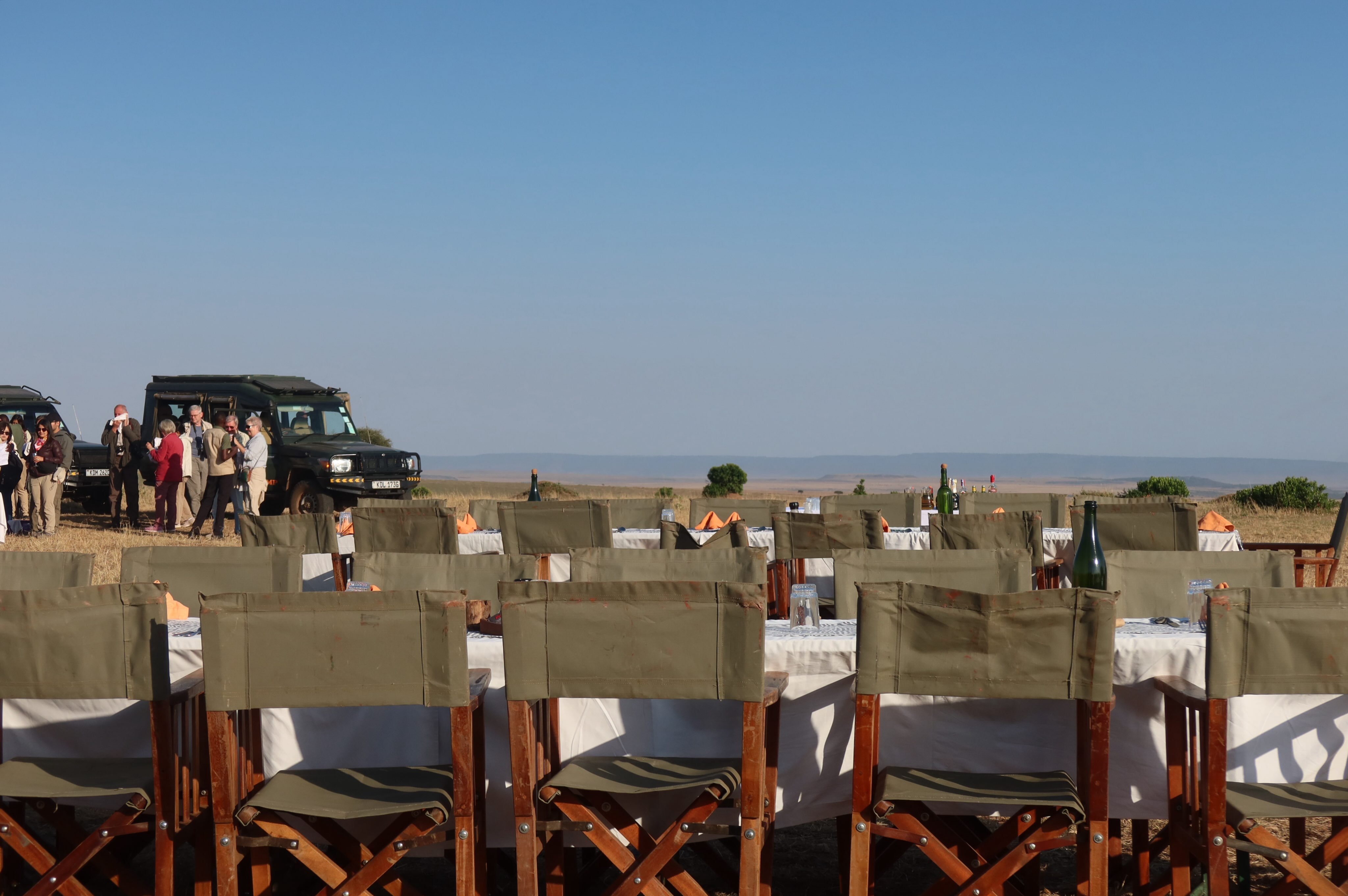 A long dining table set with safari chairs on open plains