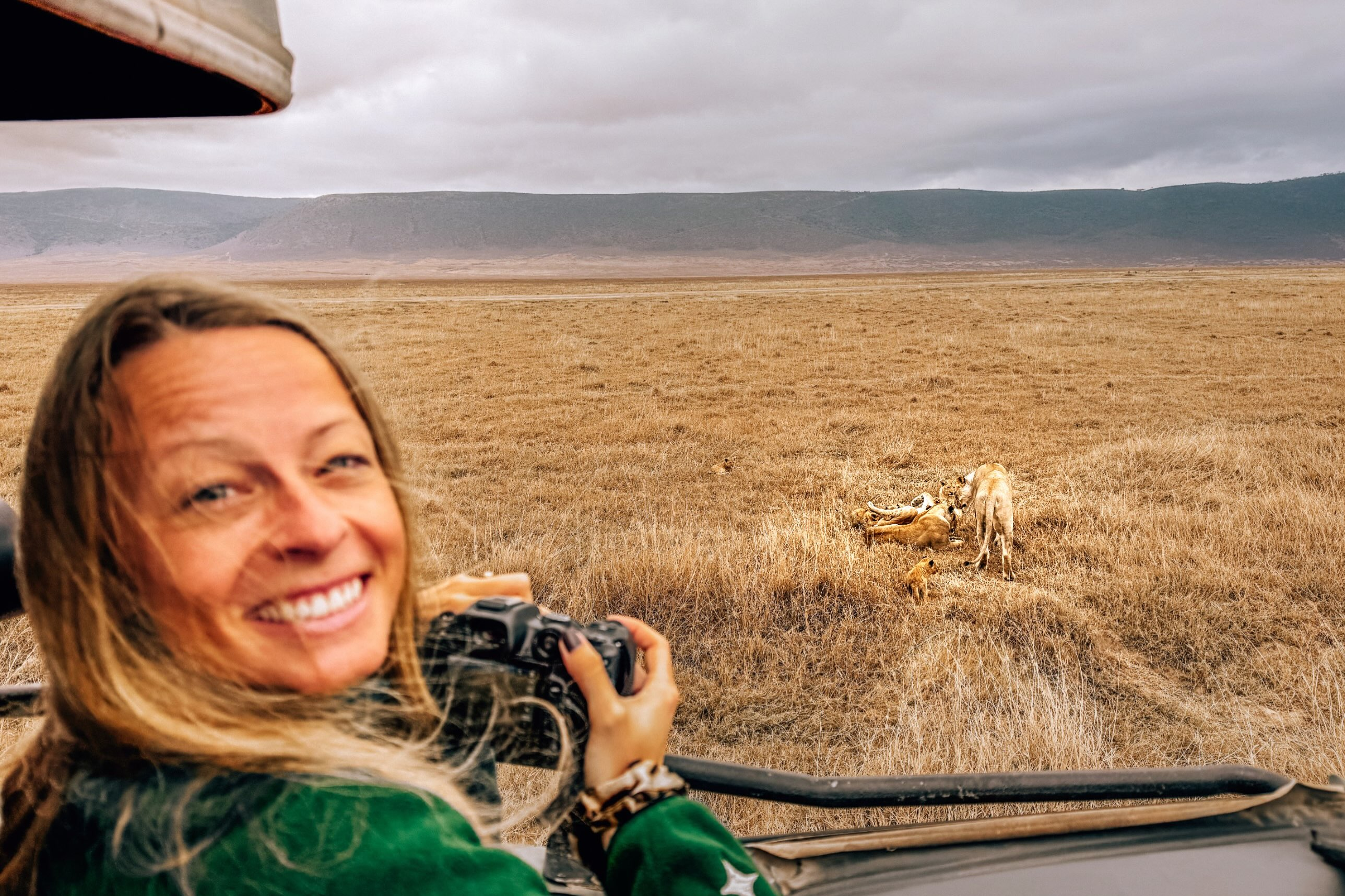 A woman with a camera on a game drive overlooking the grassy floor of Ngorongoro Crater