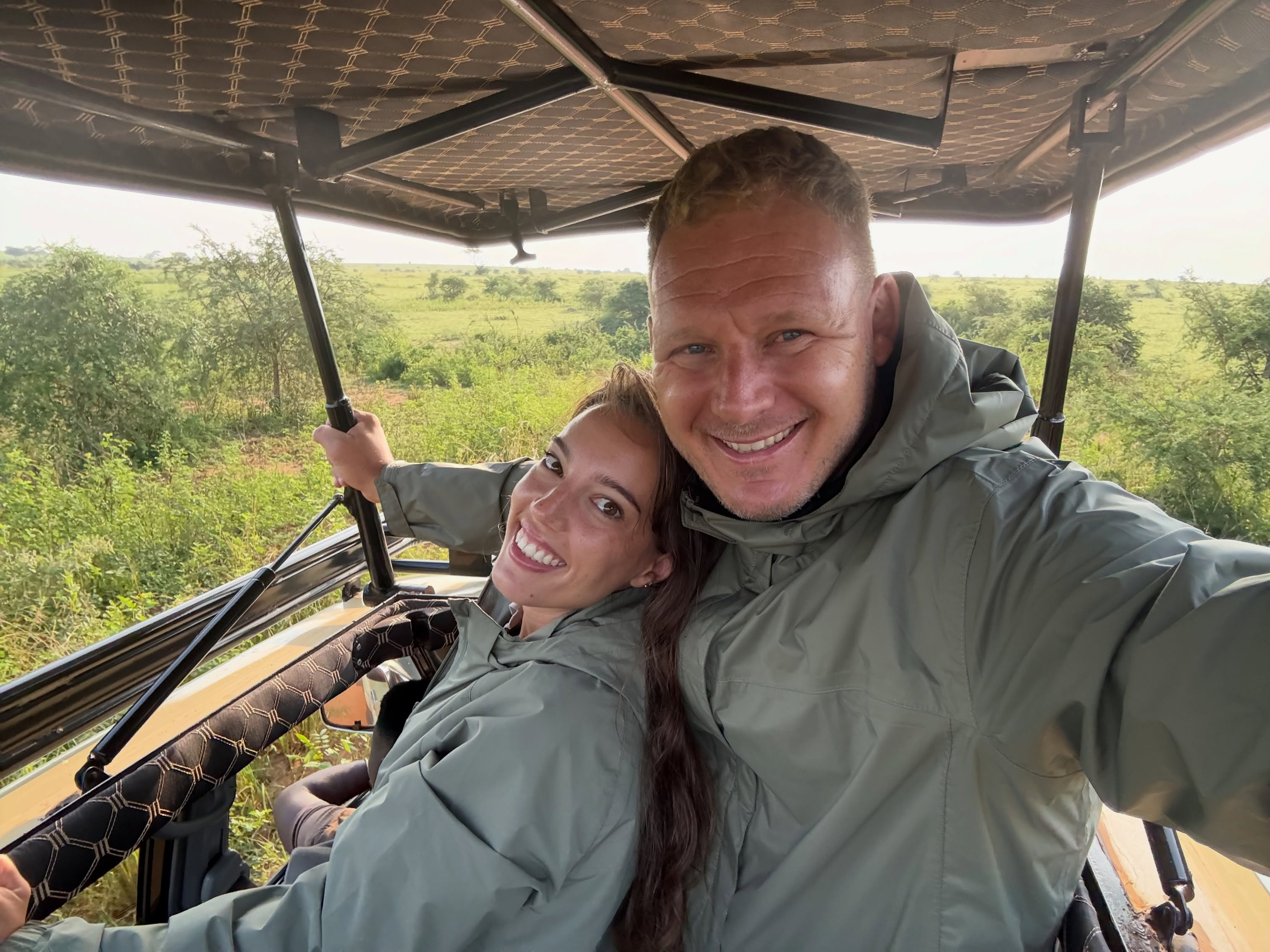 A couple smiling in the open roof of a safari vehicle