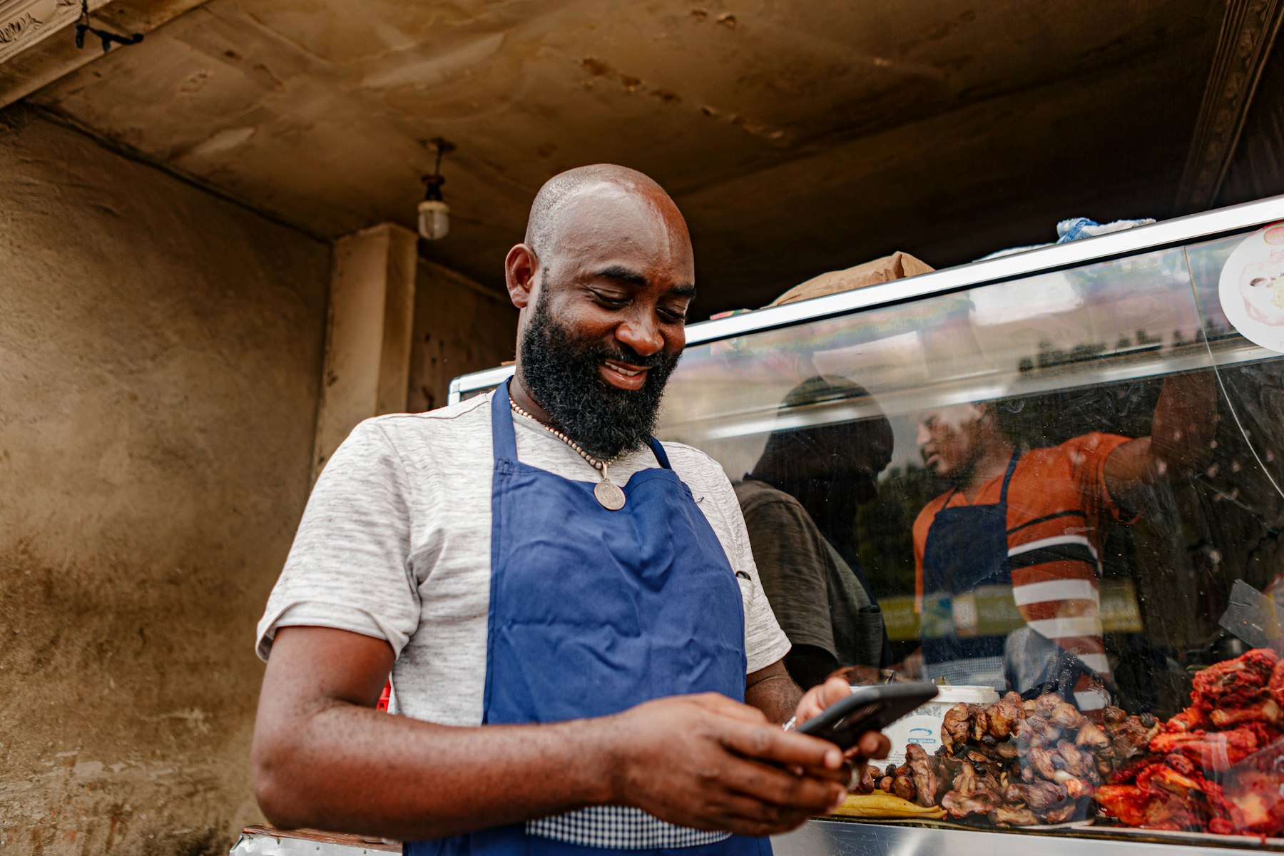 A food stall owner smiling at a new customer message on his phone