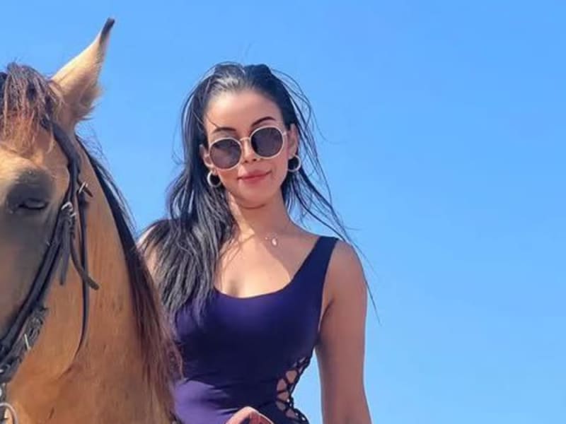 Rider standing beside a saddled horse on the beach