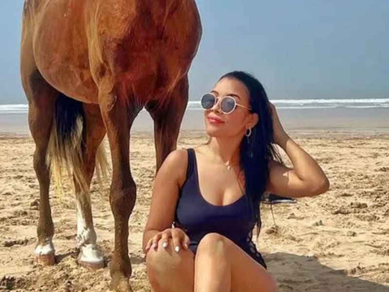 Guest sitting beside a horse on the sand at Essaouira beach