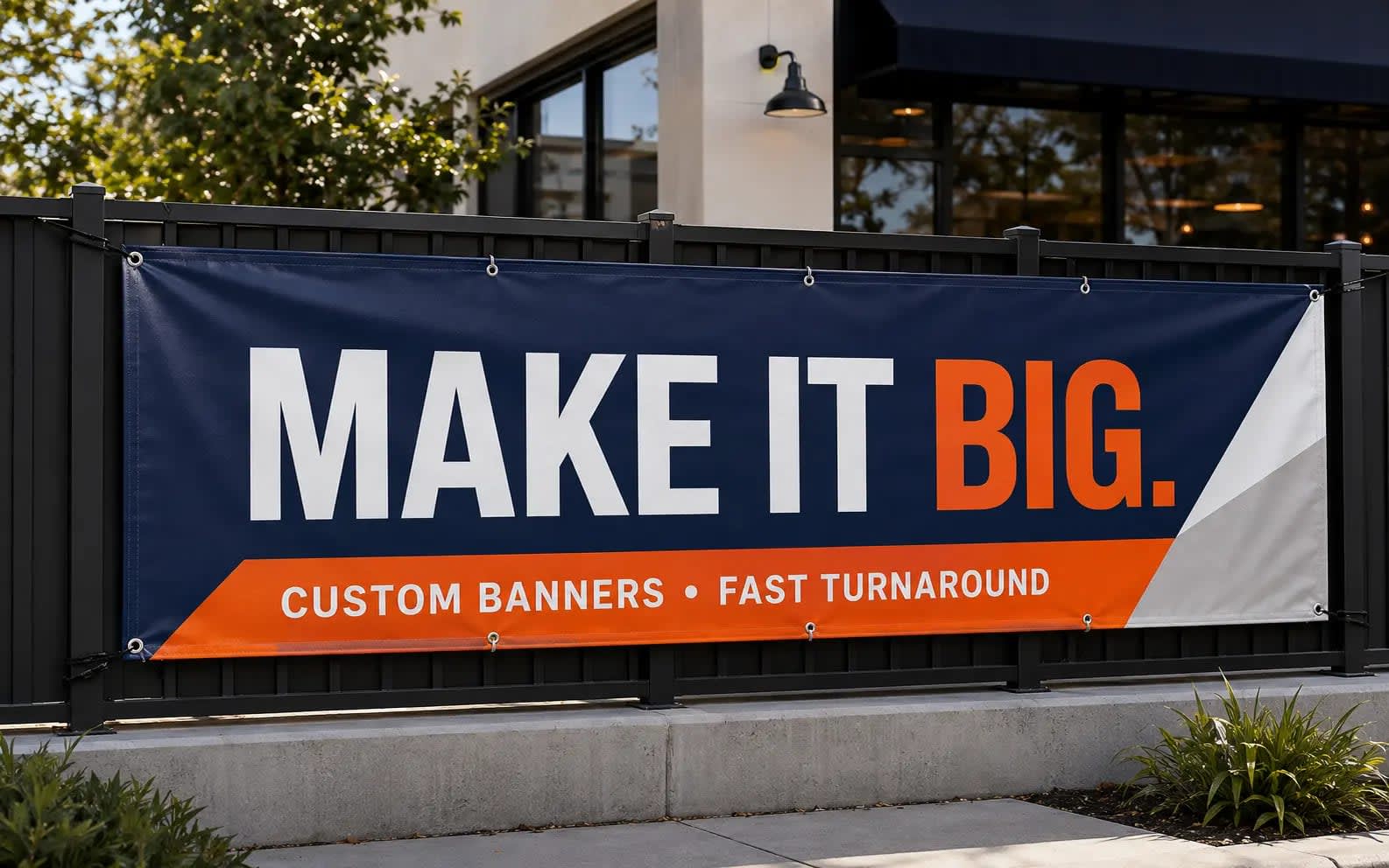 Navy and orange custom vinyl banner mounted on a black railing outside a modern storefront
