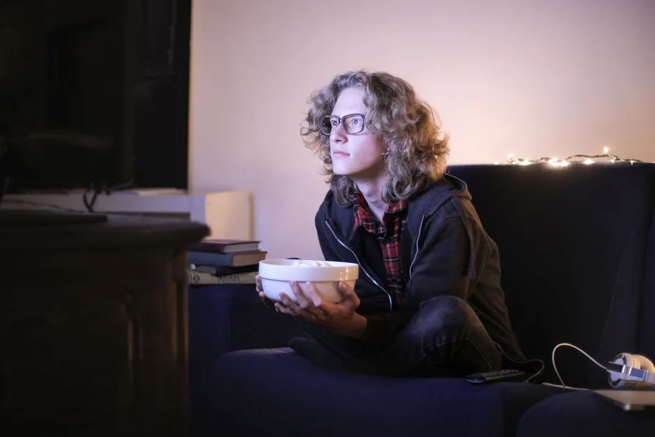 A person relaxing and watching TV on a couch at night
