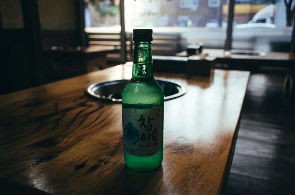 Soju glasses being poured at a Korean table