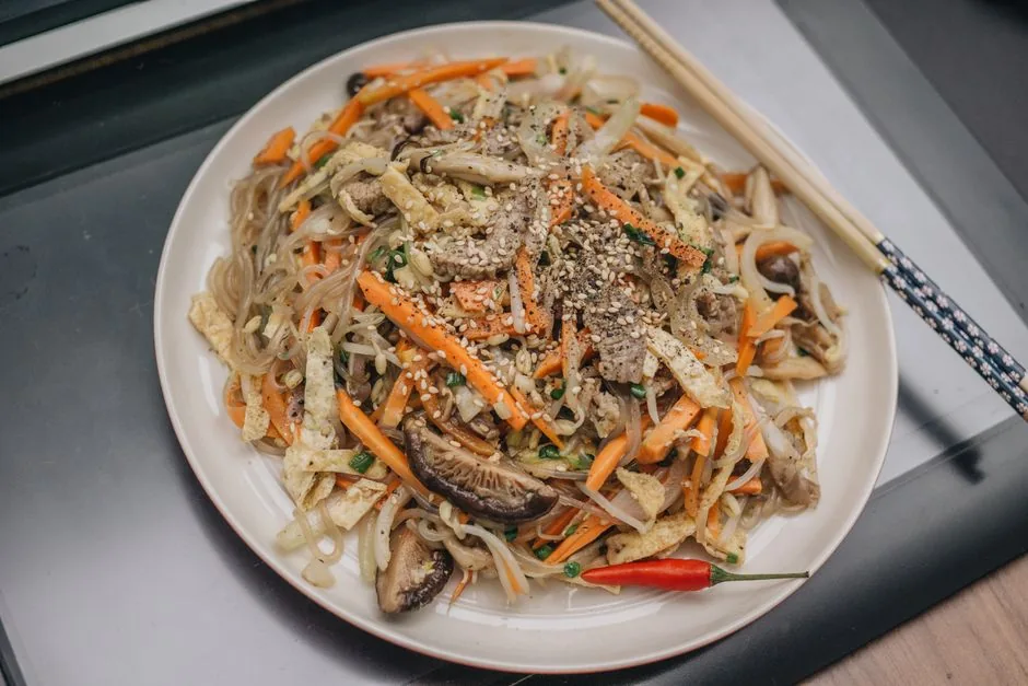 A plate of japchae glass noodles with colorful vegetables