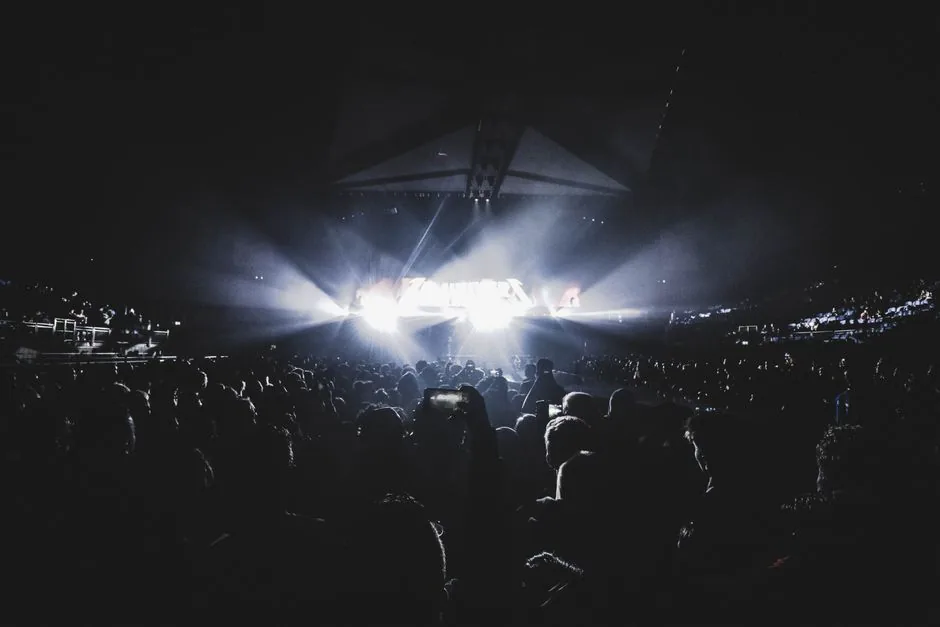 A concert arena glowing with stage lights and a packed crowd