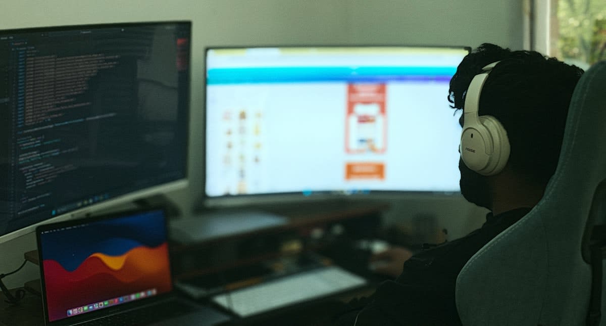 person working with multiple monitors showing code and AI interfaces