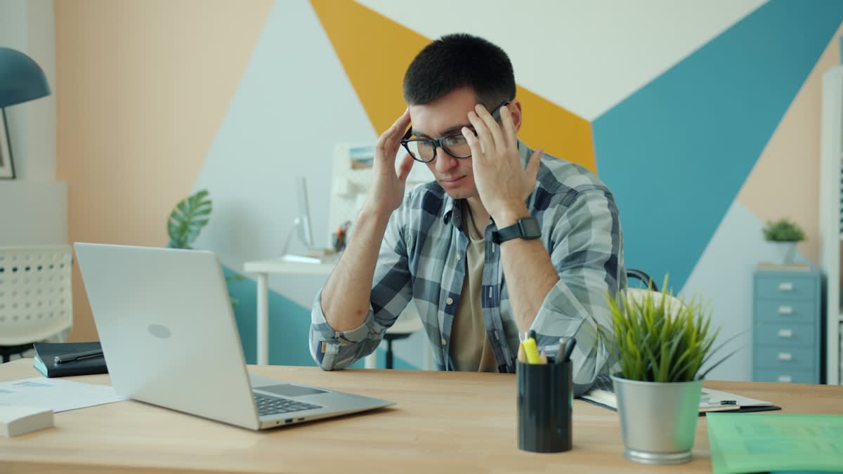 modern office worker looking stressed at a computer