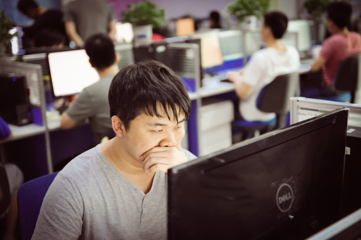 stressed professional looking at multiple screens in a modern office