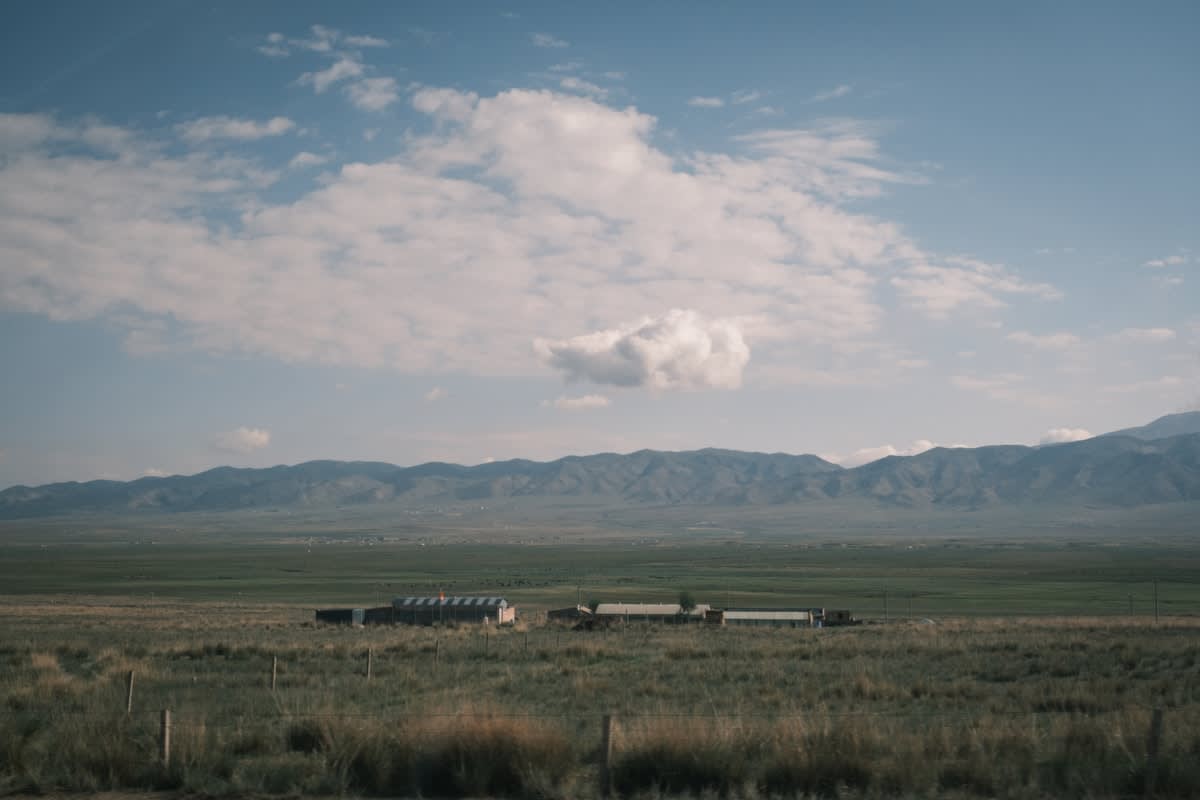A long freight train carrying containers through a rural landscape