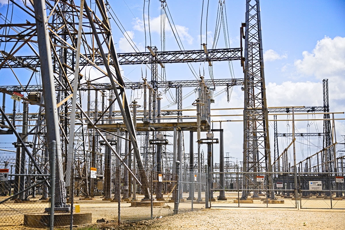 Close up of high-voltage power lines and a gas turbine plant