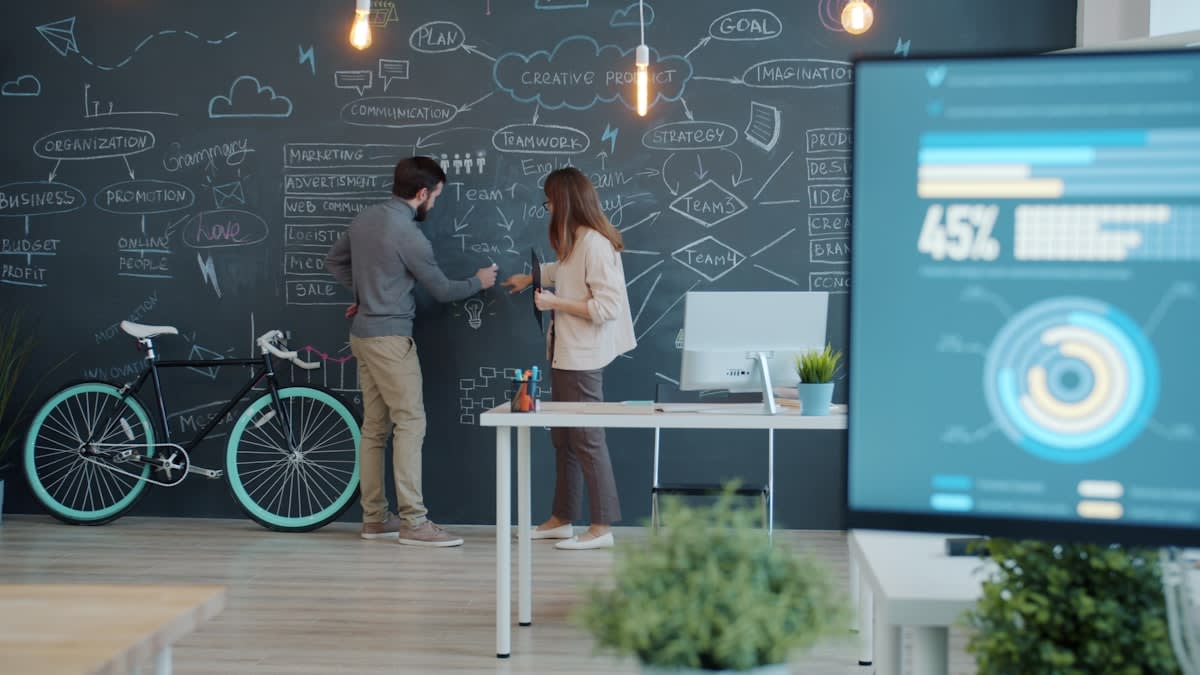 A diverse team of professionals analyzing data on a large screen in a modern office