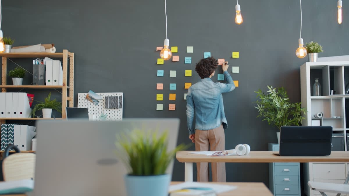 A large office wall covered in colorful sticky notes and complex diagrams