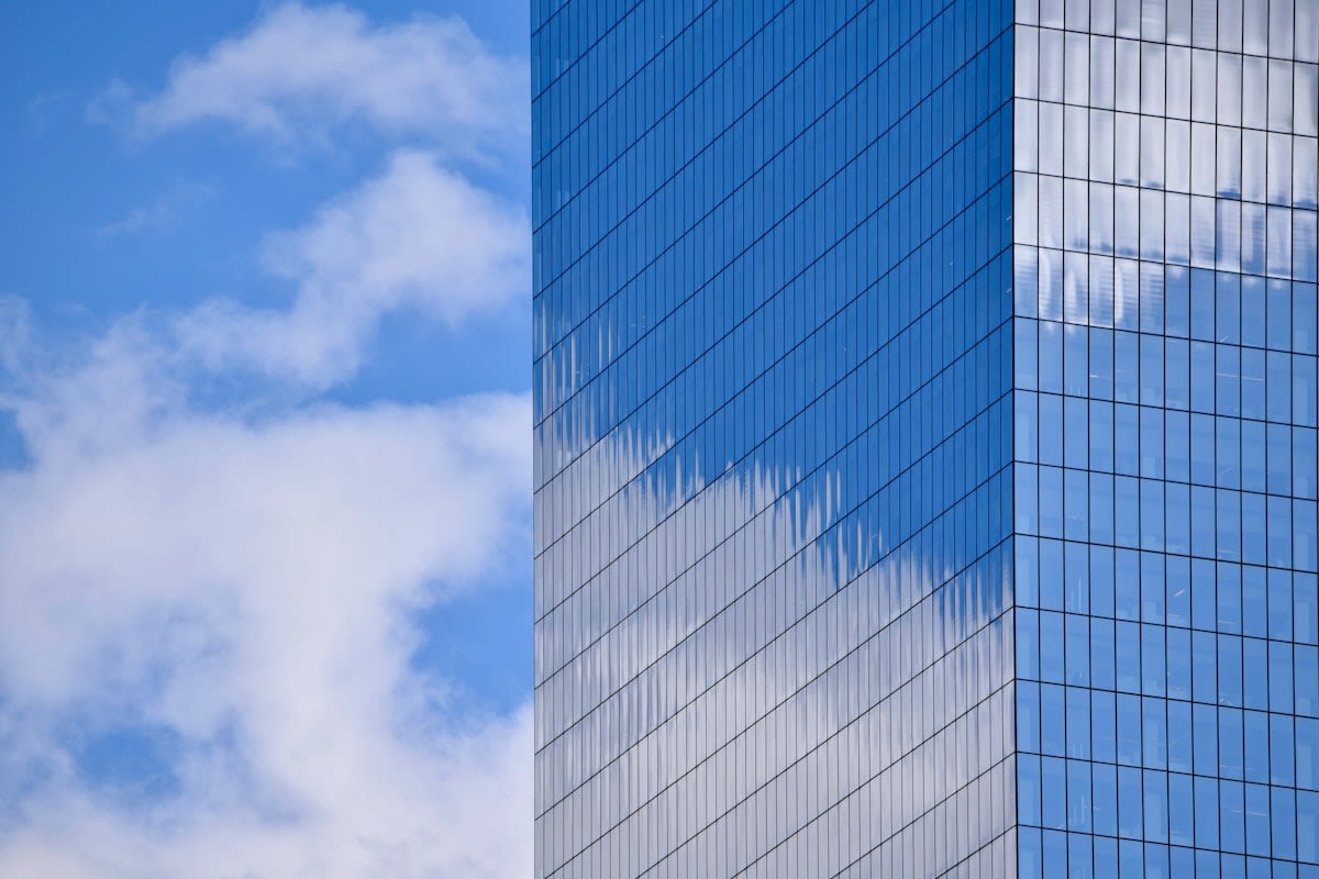 Modern glass skyscraper reflecting a cloudy sky