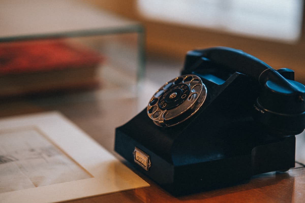 A simple, old-fashioned analog phone on a wooden table