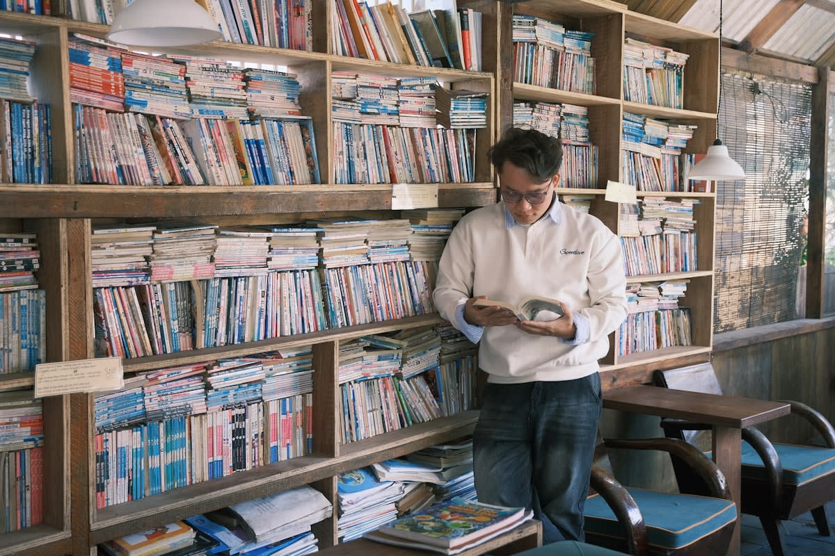 A focused person reading a physical book in a quiet library