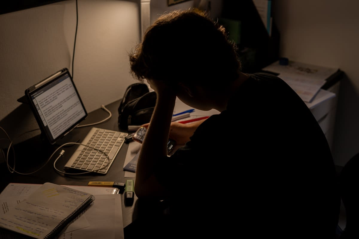 person looking stressed at a desk with many papers