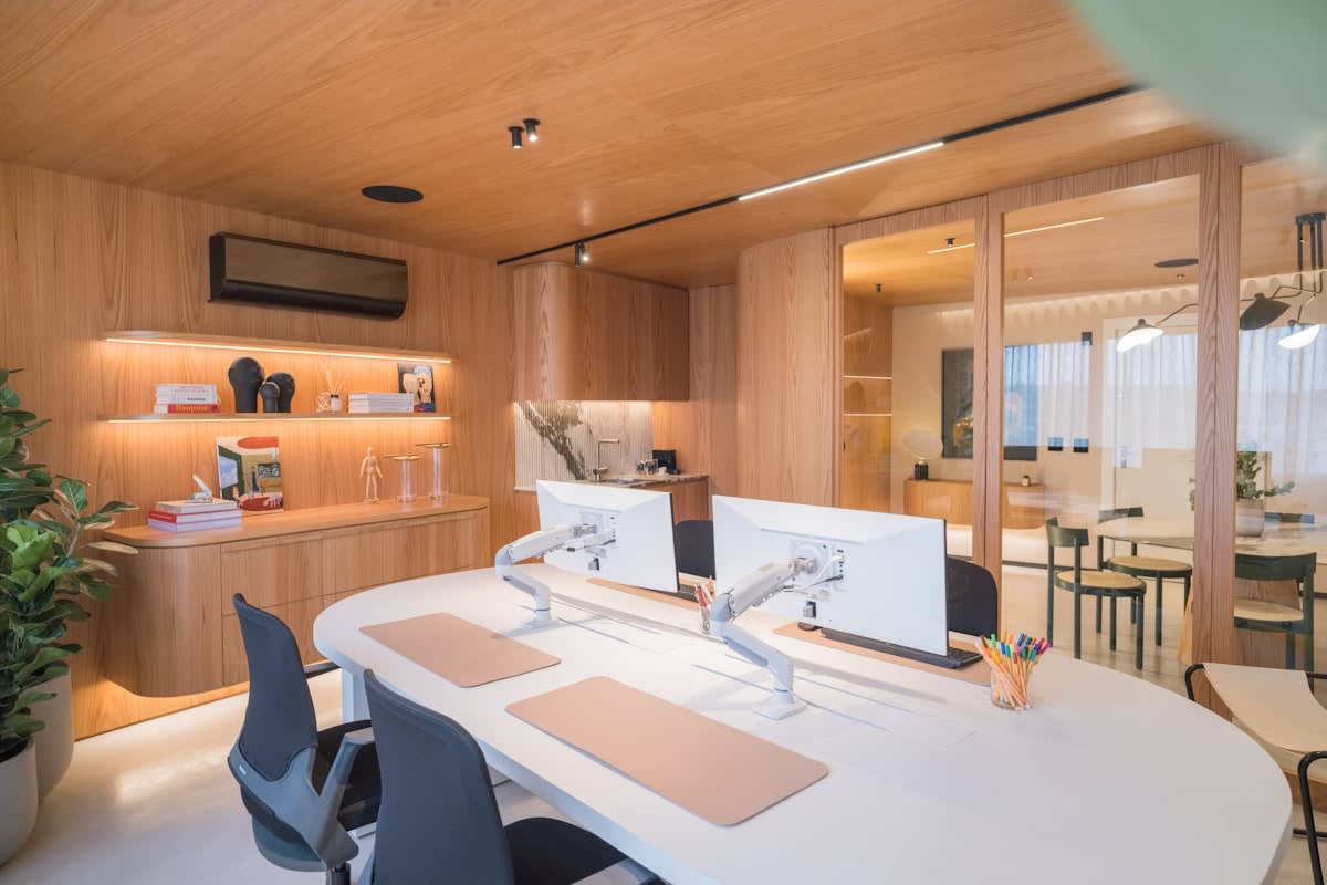 Modern minimalist home office with multiple screens showing data dashboards